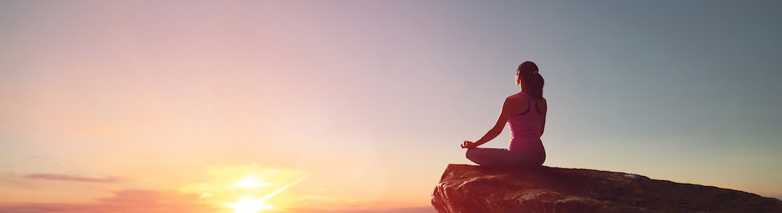 Tantra yoga woman sitting on rock at sunset